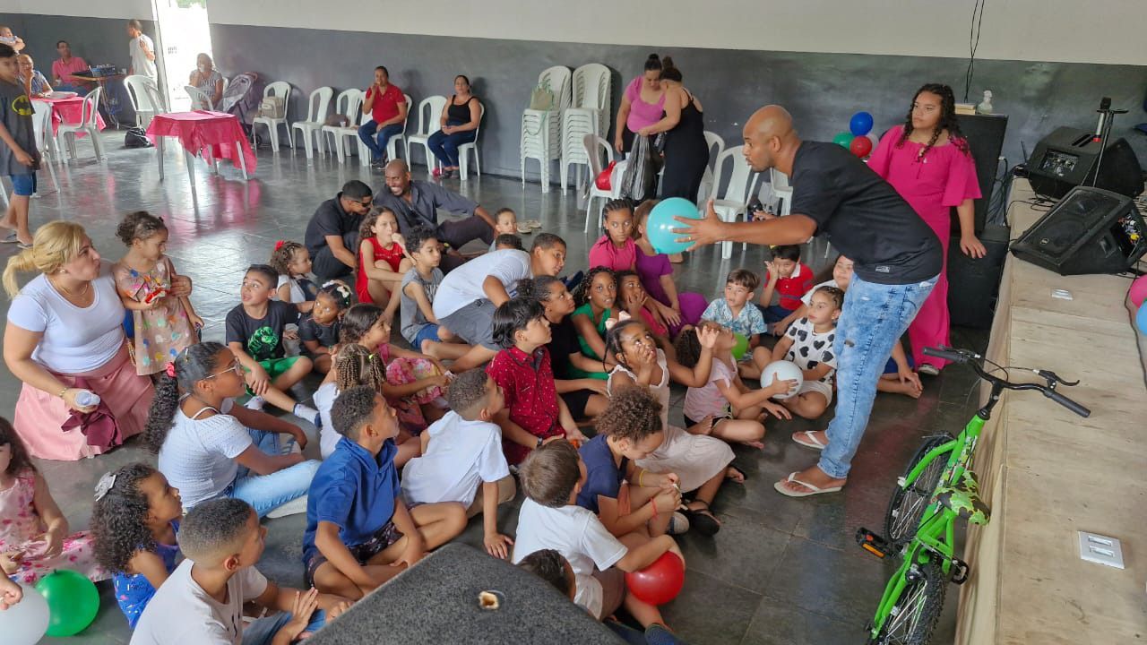Um grupo de crianças está sentado no chão de uma sala.