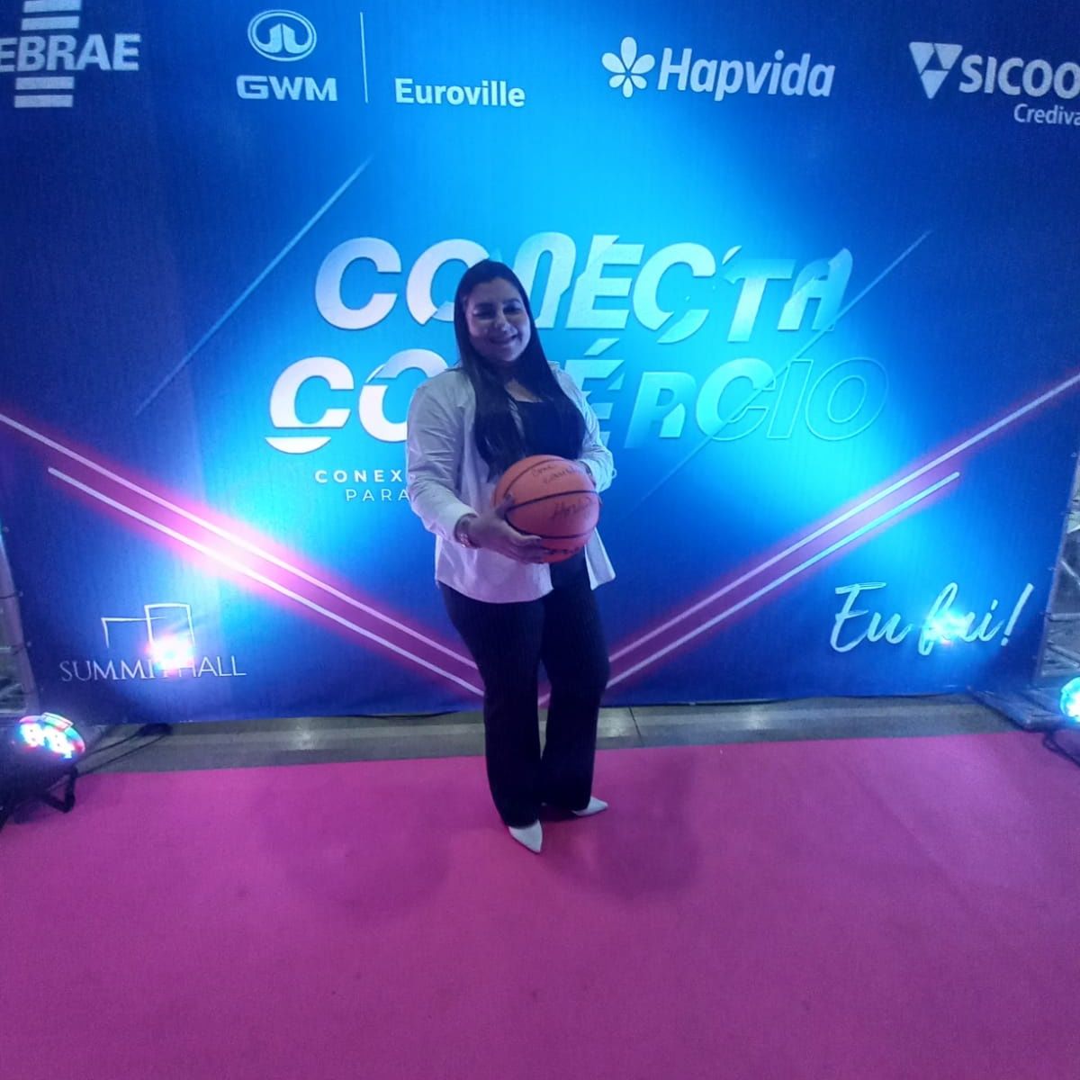 Uma mulher segurando uma bola de basquete em frente a uma parede que diz conecta