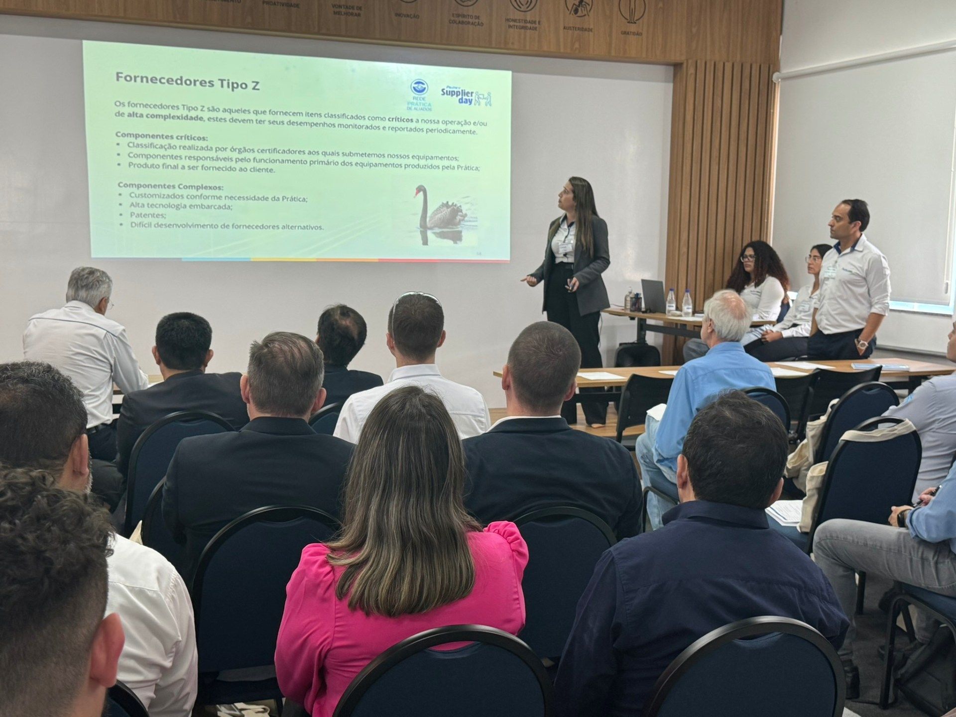 Uma mulher está fazendo uma apresentação para um grupo de pessoas em uma sala de conferências.