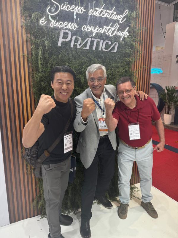 Três homens estão posando para uma foto em frente a uma parede que diz pratica