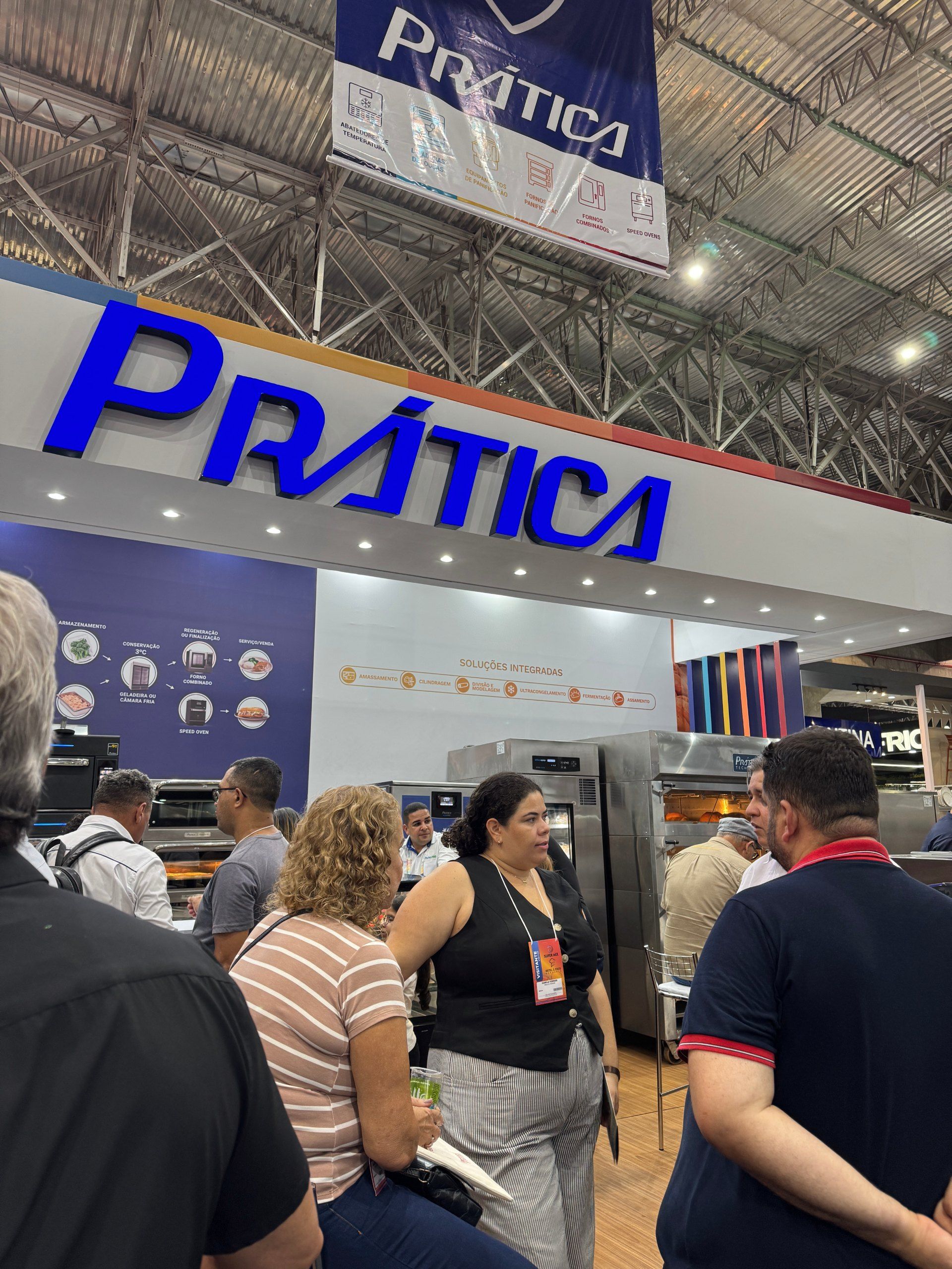 Pessoas em um estande de feira comercial com uma placa azul 