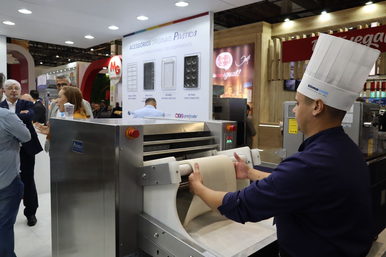 Um homem usando um chapéu de chef está trabalhando em uma máquina.