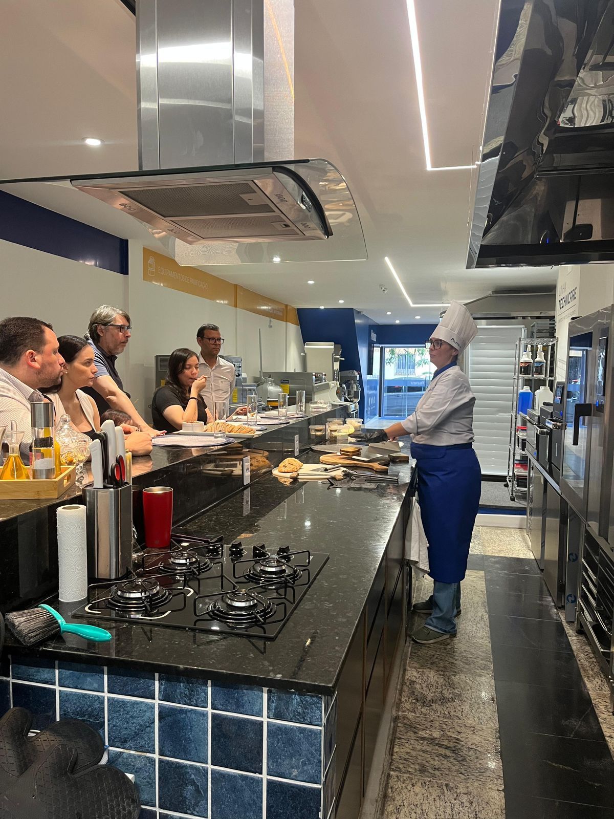 Chef demonstra técnicas de culinária para um grupo de pessoas em uma cozinha.
