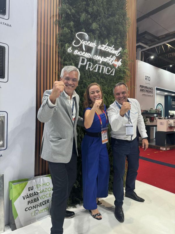 Três pessoas estão posando para uma foto em frente a uma placa que diz pratica.