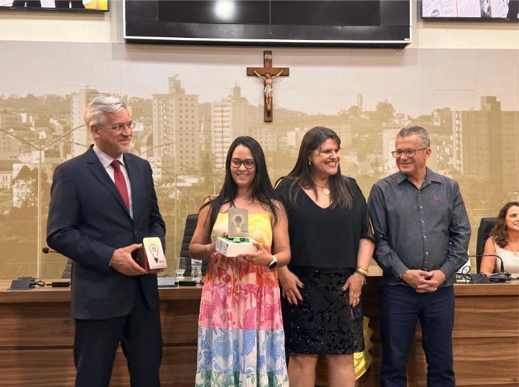 Um grupo de pessoas em pé, uma ao lado da outra, em frente a uma cruz.
