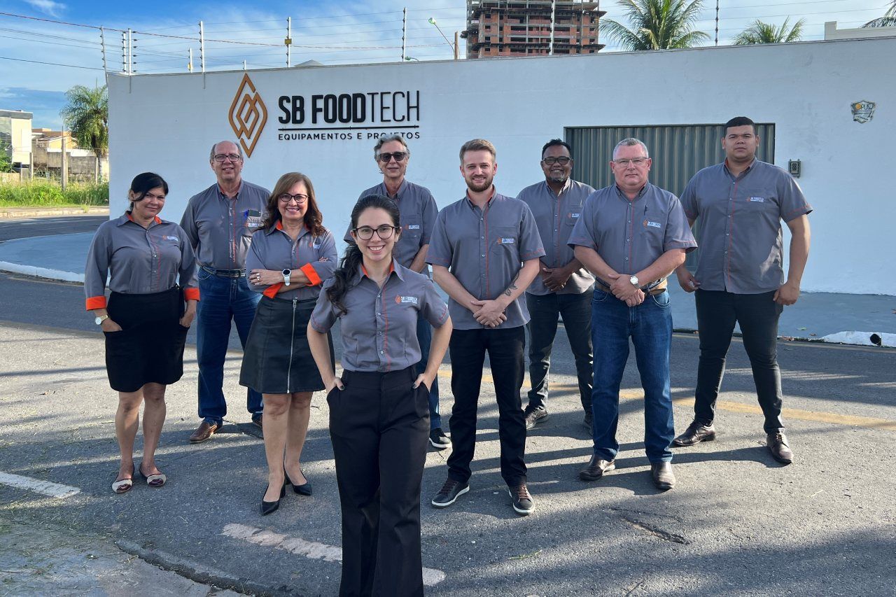 Um grupo de pessoas está posando para uma foto em frente a um prédio.