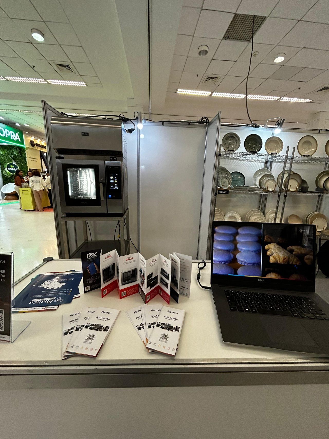 Um laptop está sobre uma mesa em frente a uma vitrine.