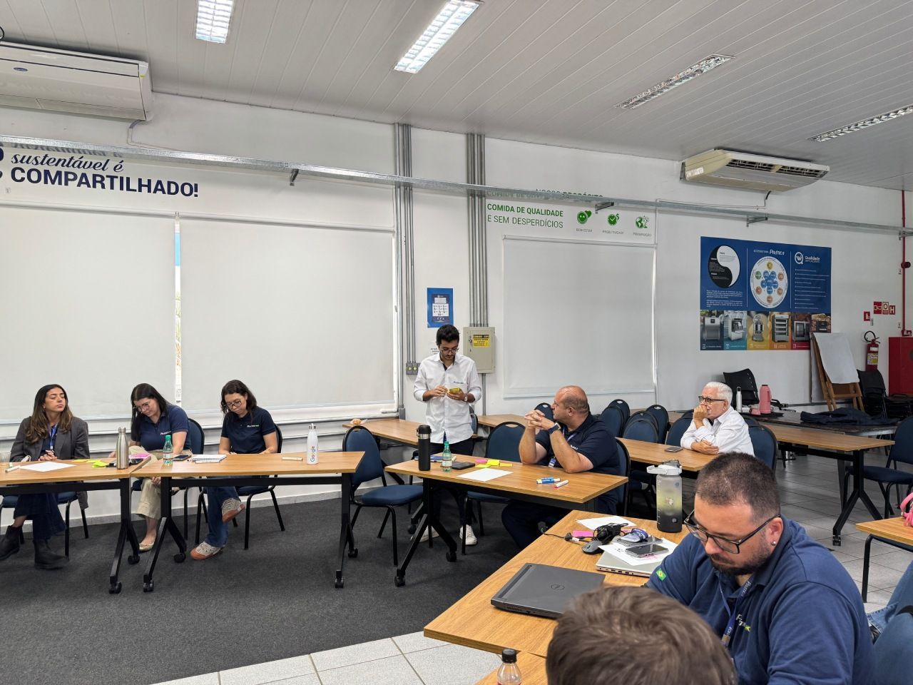 Um grupo de pessoas está sentado à mesa em uma sala de reuniões de escritório