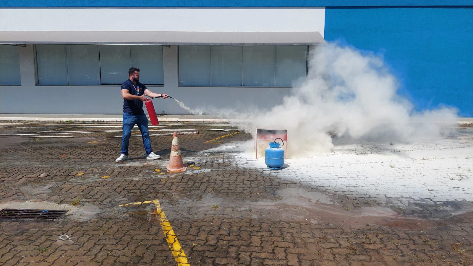 Um homem está usando um extintor de incêndio para apagar um incêndio em um estacionamento.