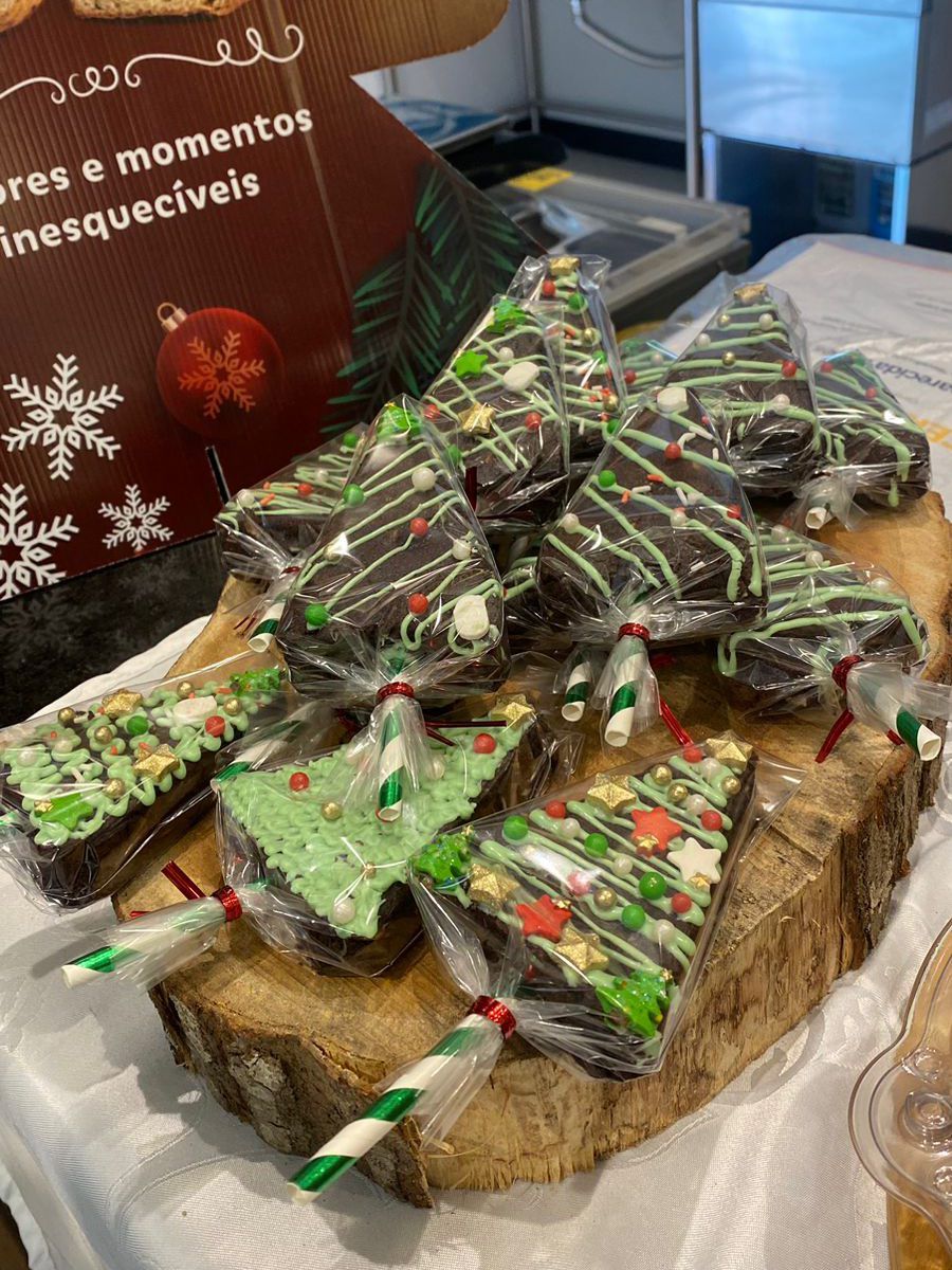 Uma tábua de corte de madeira coberta com brownies em formato de árvores de natal.