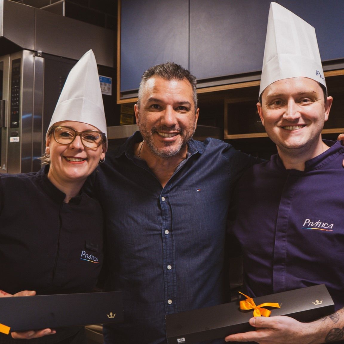 Três pessoas usando chapéus de chef posando para uma foto
