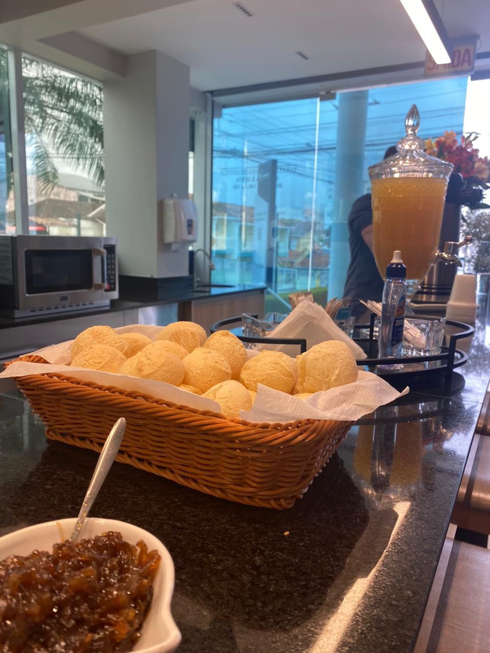 Uma cesta de pães está sobre um balcão ao lado de uma tigela de geleia.