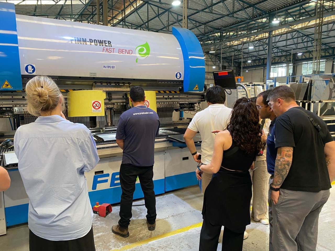 Um grupo de pessoas está em volta de uma máquina em uma fábrica.