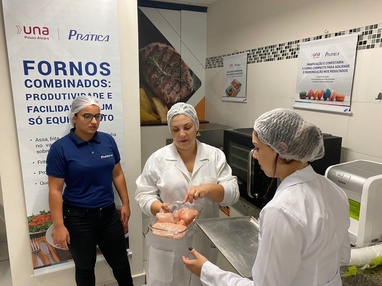 Três mulheres estão em uma sala com uma placa que diz fornos combinados