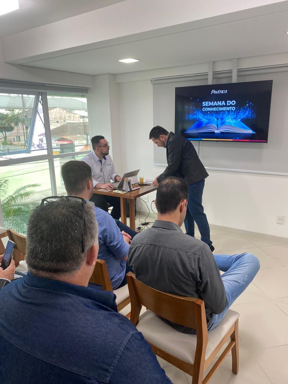 Um grupo de homens está sentado em uma sala assistindo a uma apresentação.