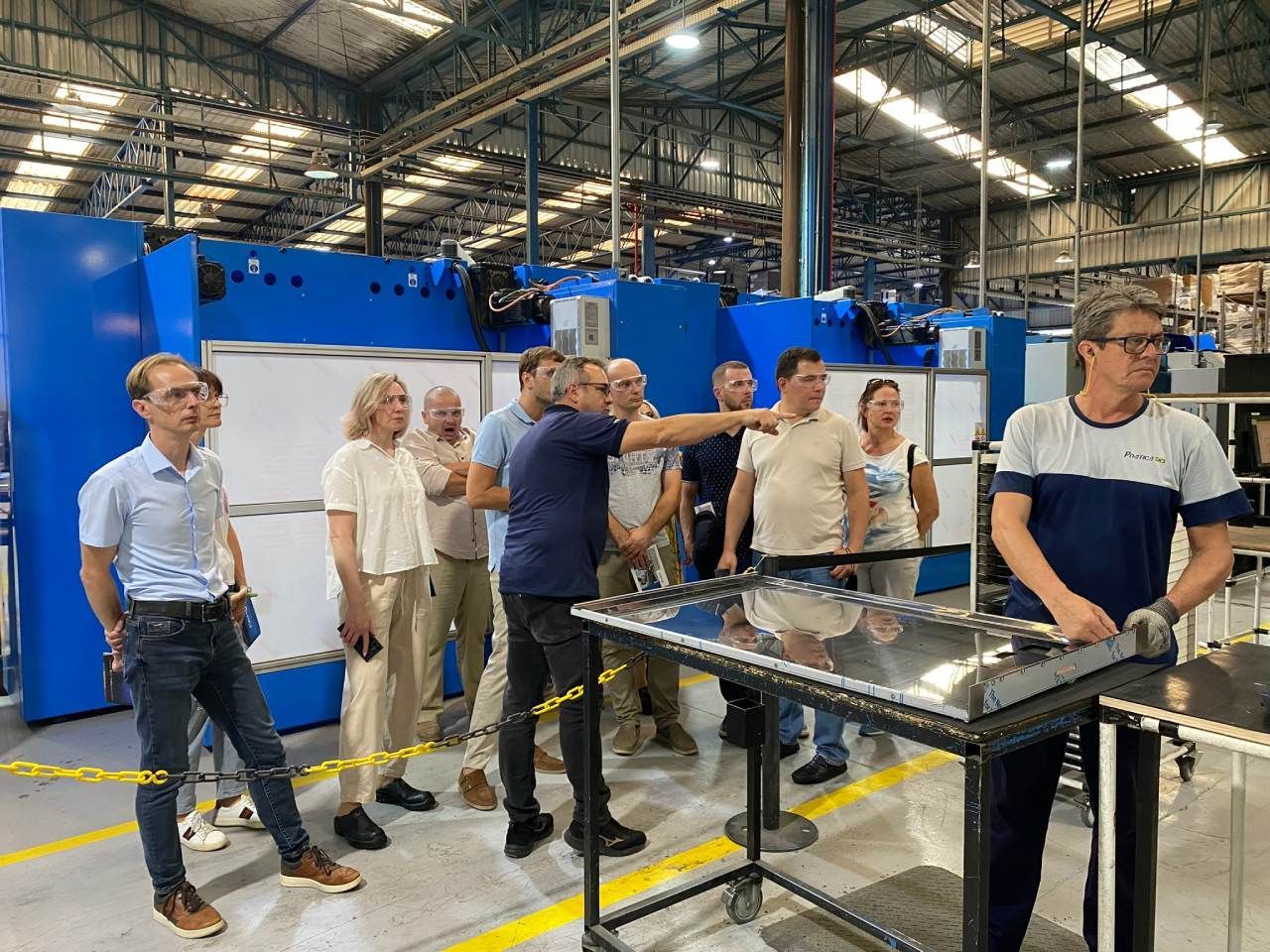Um grupo de pessoas está em volta de uma mesa em uma fábrica.