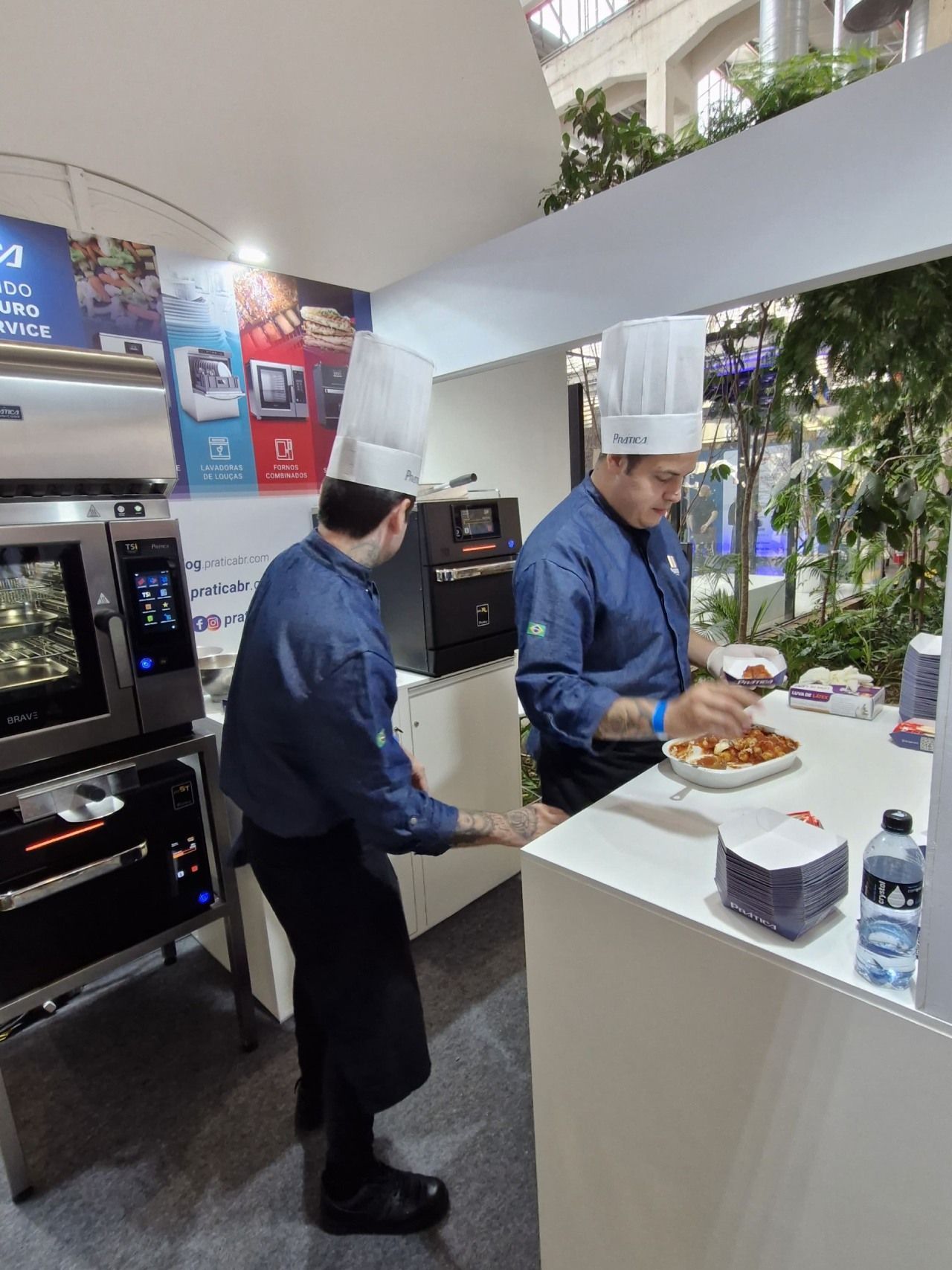 Dois homens com chapéus de chef estão preparando comida em uma cozinha