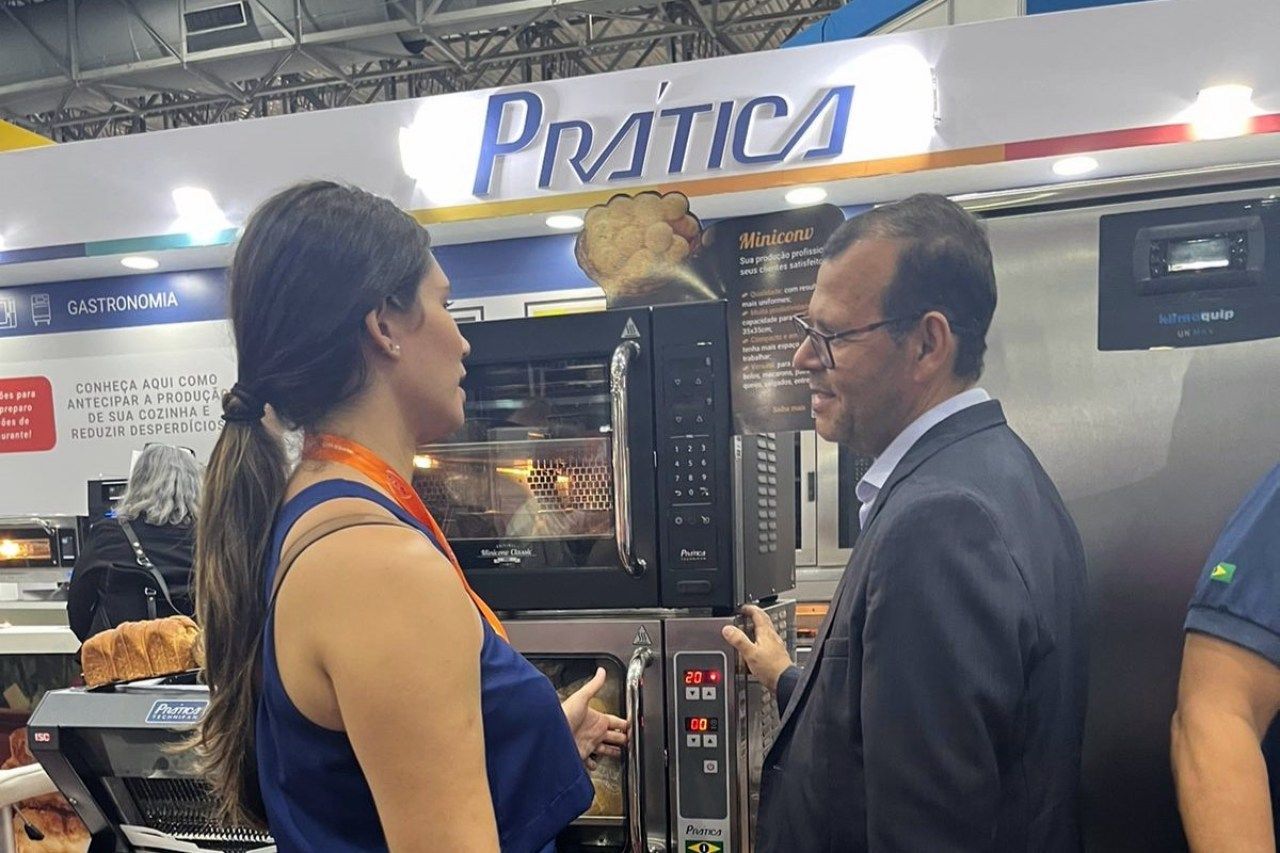 Um homem e uma mulher estão conversando em frente a uma placa que diz pratica