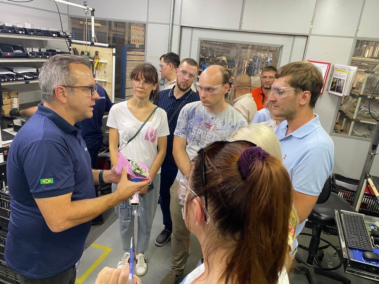 Um homem está conversando com um grupo de pessoas em uma fábrica.