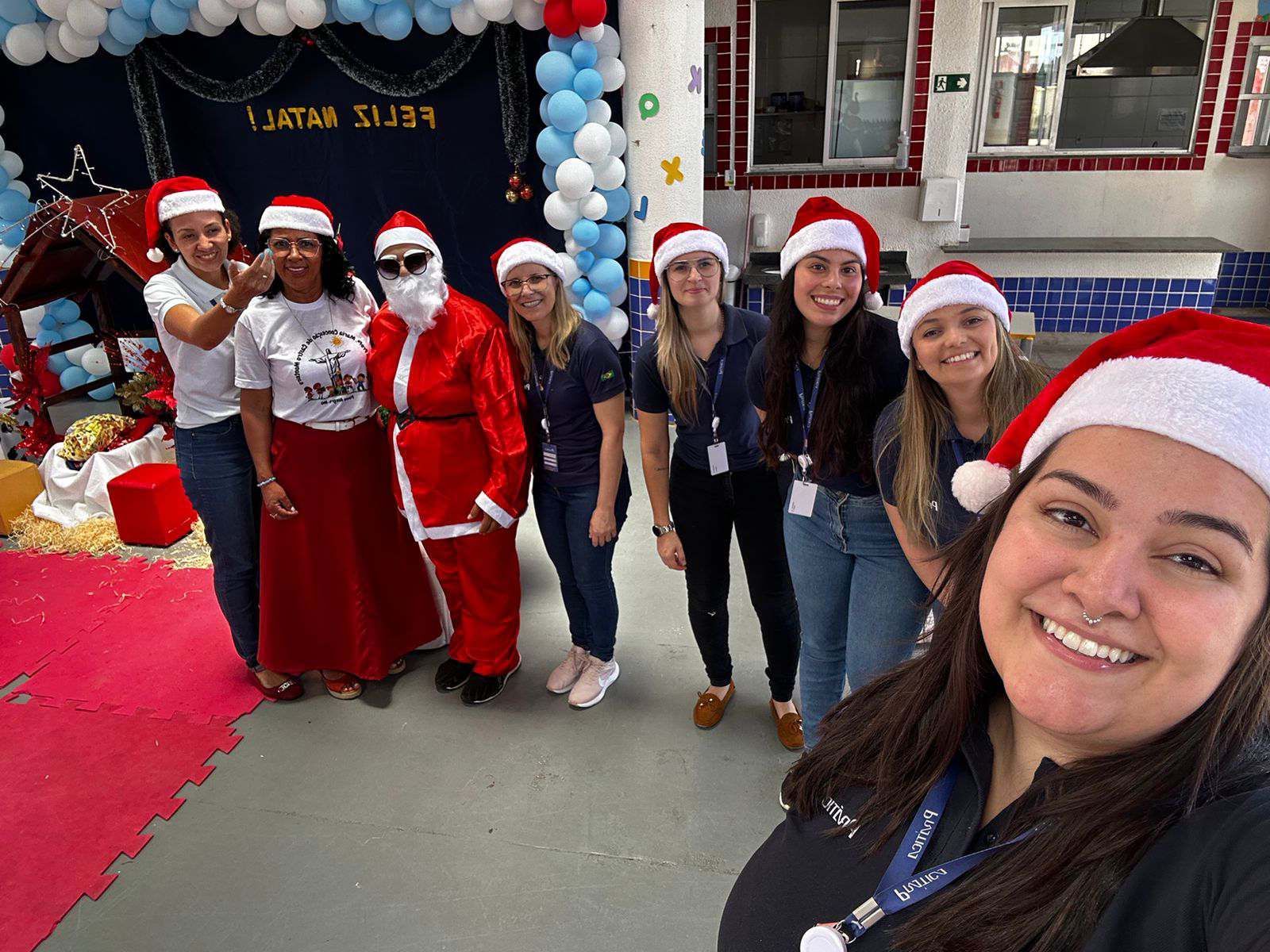 Um grupo de pessoas usando chapéus de Papai Noel estão posando para uma foto.
