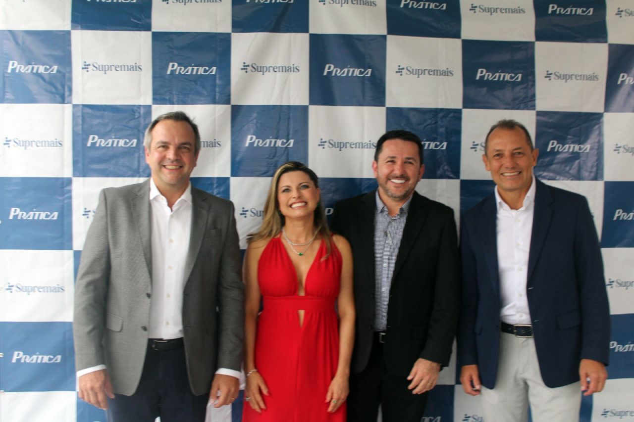 Uma mulher de vestido vermelho fica entre dois homens de terno