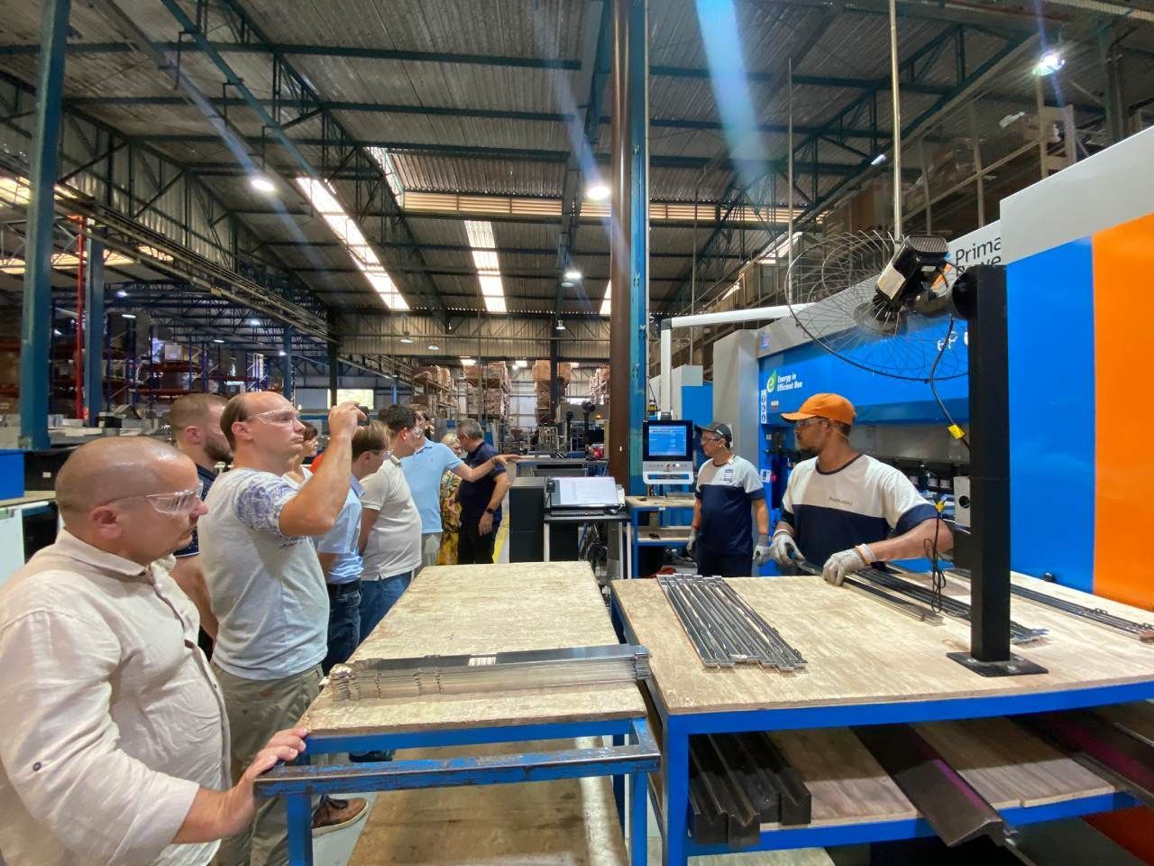 Um grupo de homens está em uma fábrica olhando para uma máquina.