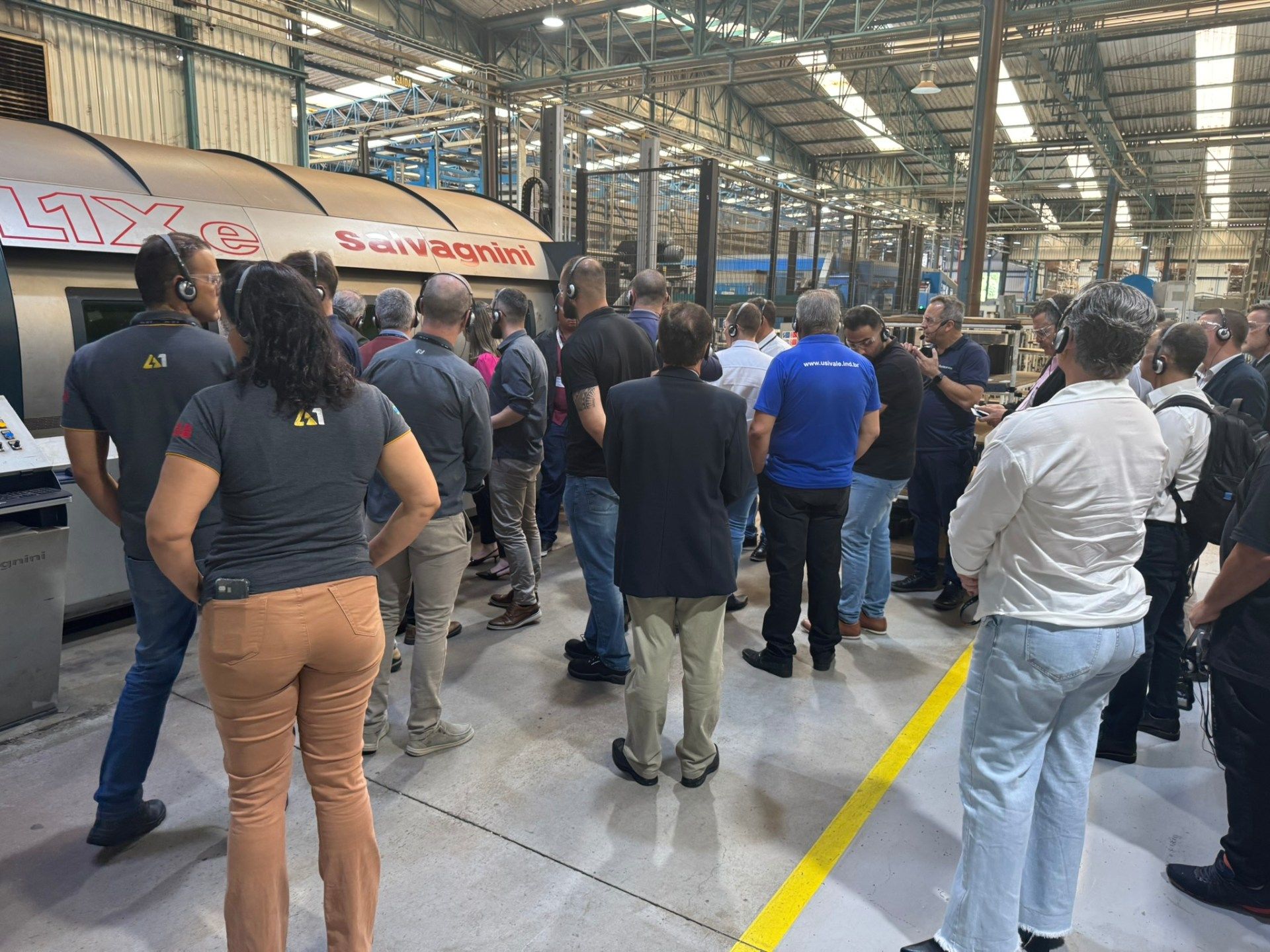 Um grupo de pessoas está em um armazém olhando para uma máquina.