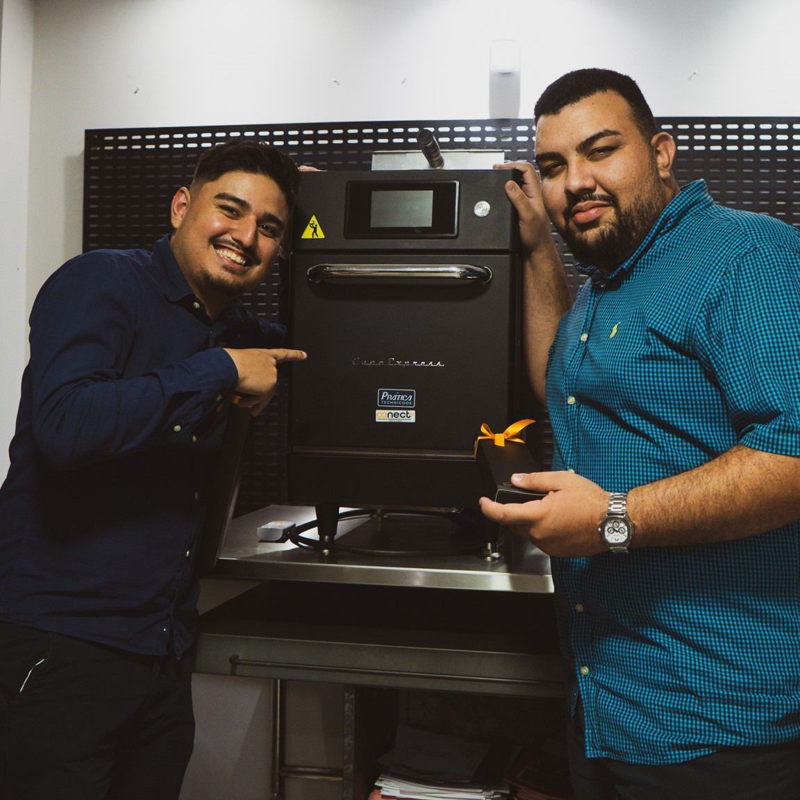 Dois homens parados um ao lado do outro em frente a um forno