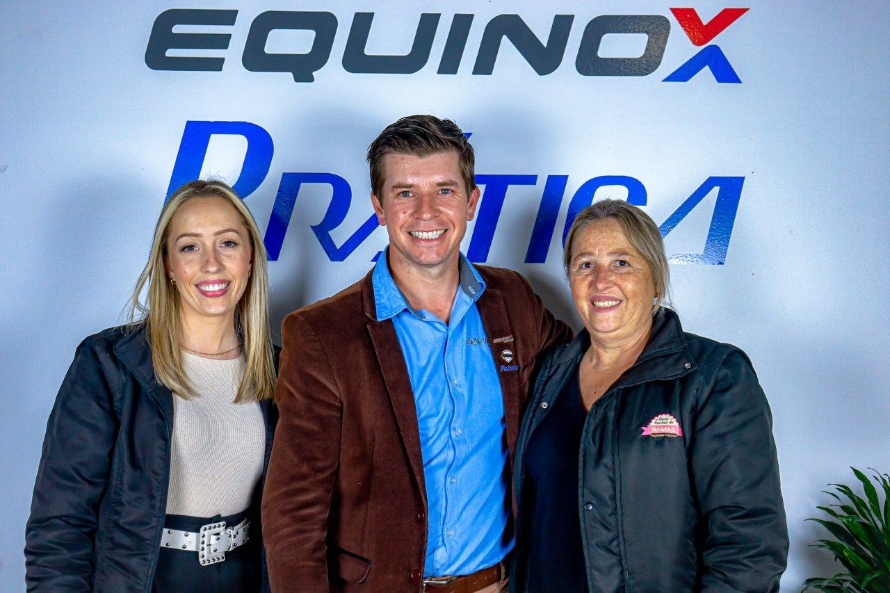 Um homem e duas mulheres estão posando para uma foto em frente ao logotipo do equinócio.