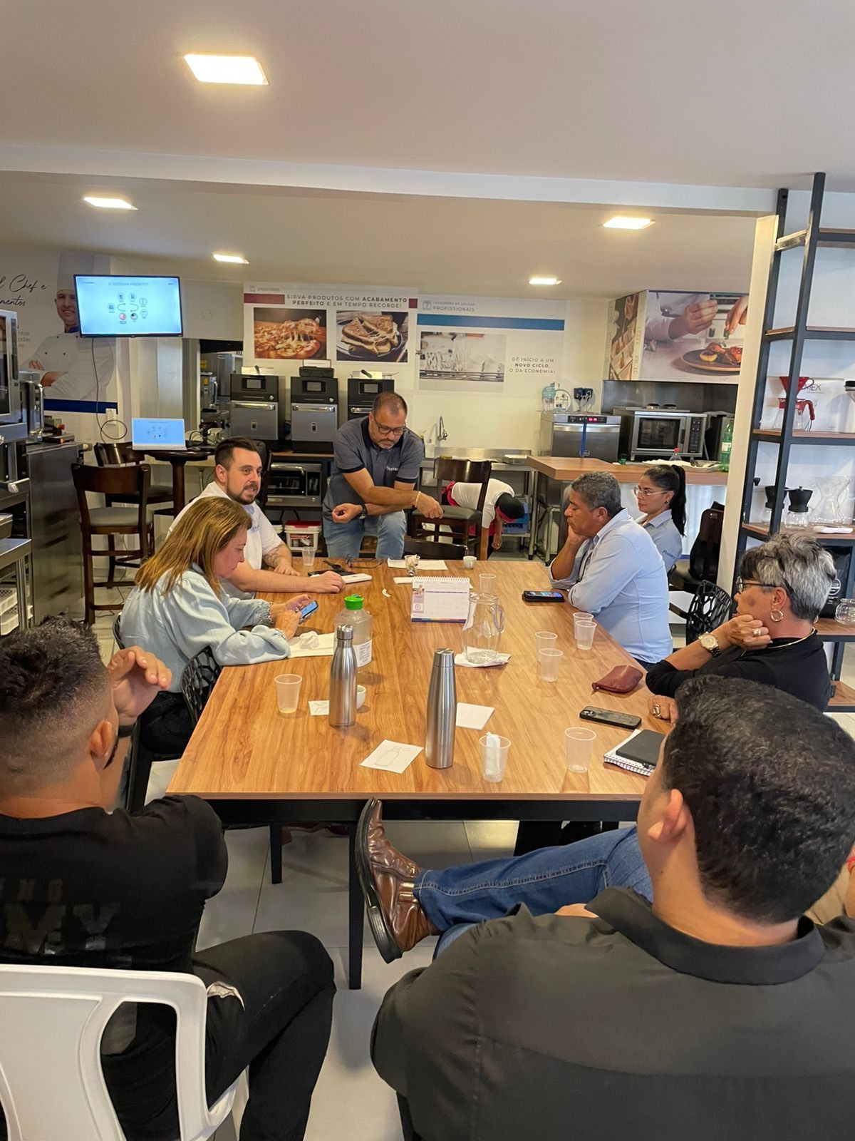Um grupo de pessoas está sentado ao redor de uma mesa em um restaurante.