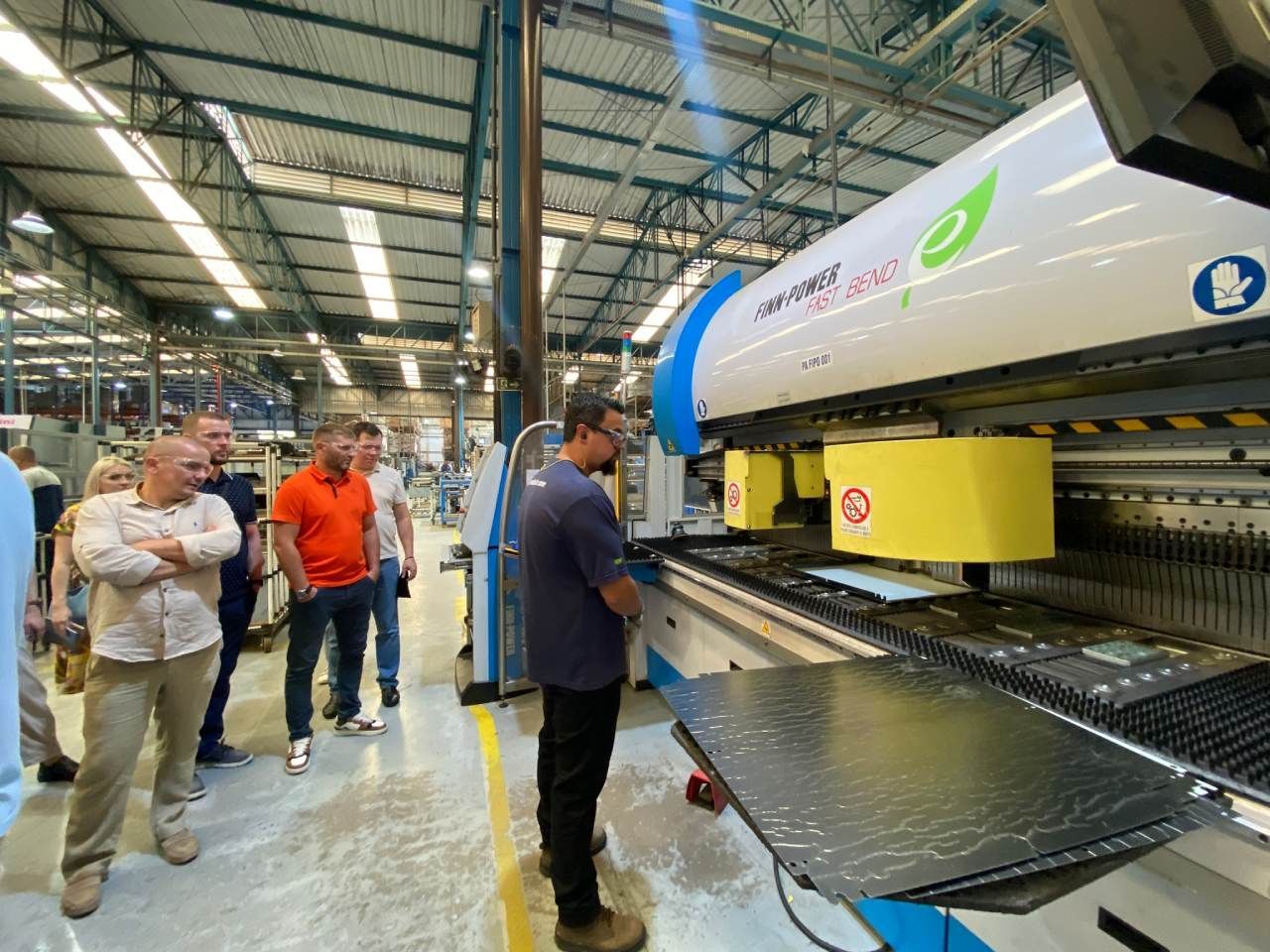 Um homem está parado em frente a uma máquina em uma fábrica.