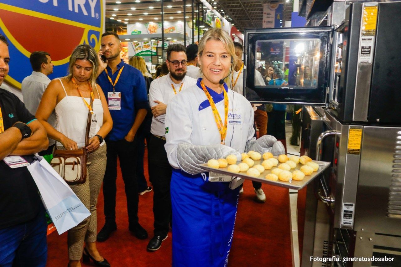 Uma mulher está segurando uma bandeja de comida em frente a um forno.