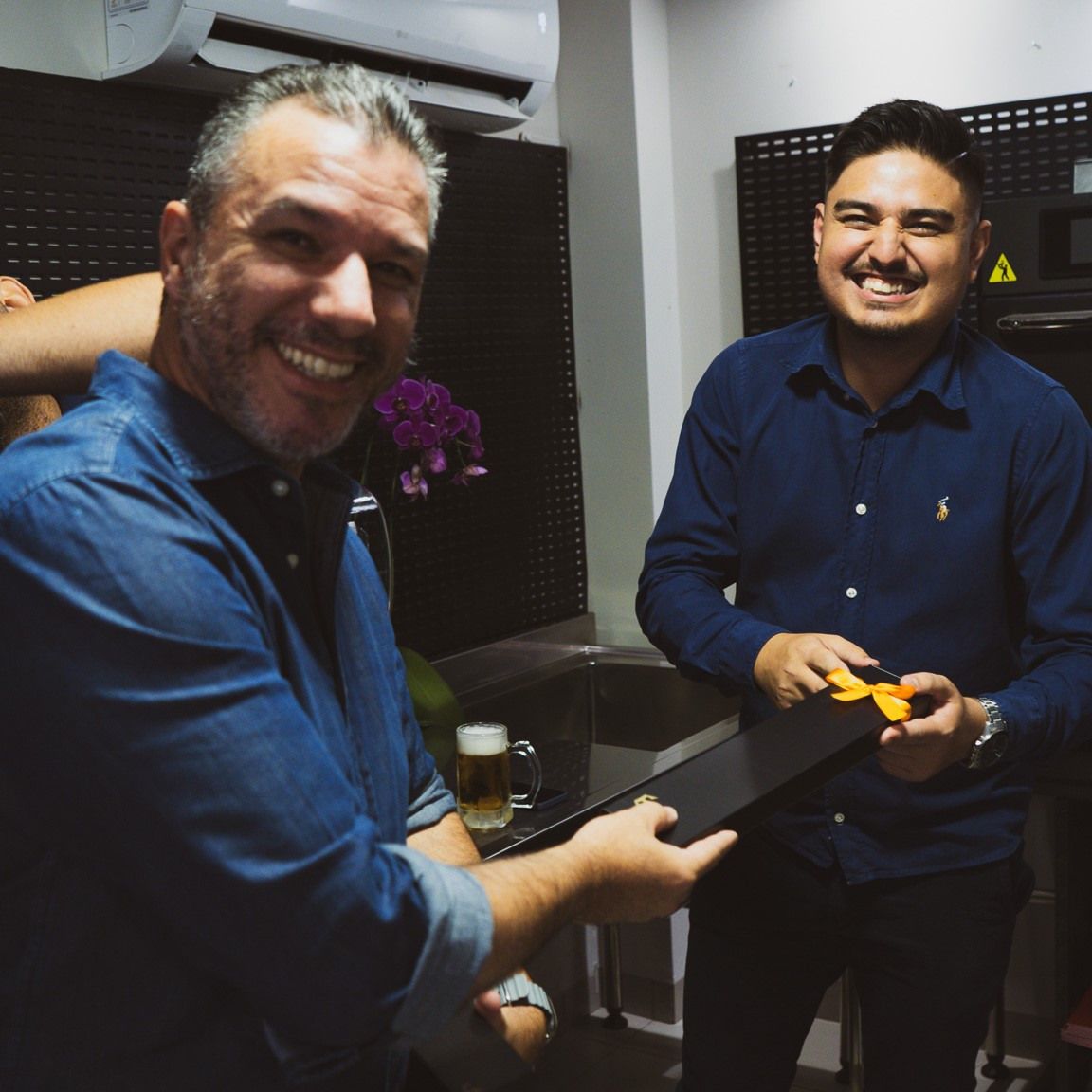Dois homens estão parados um ao lado do outro e sorrindo para a câmera