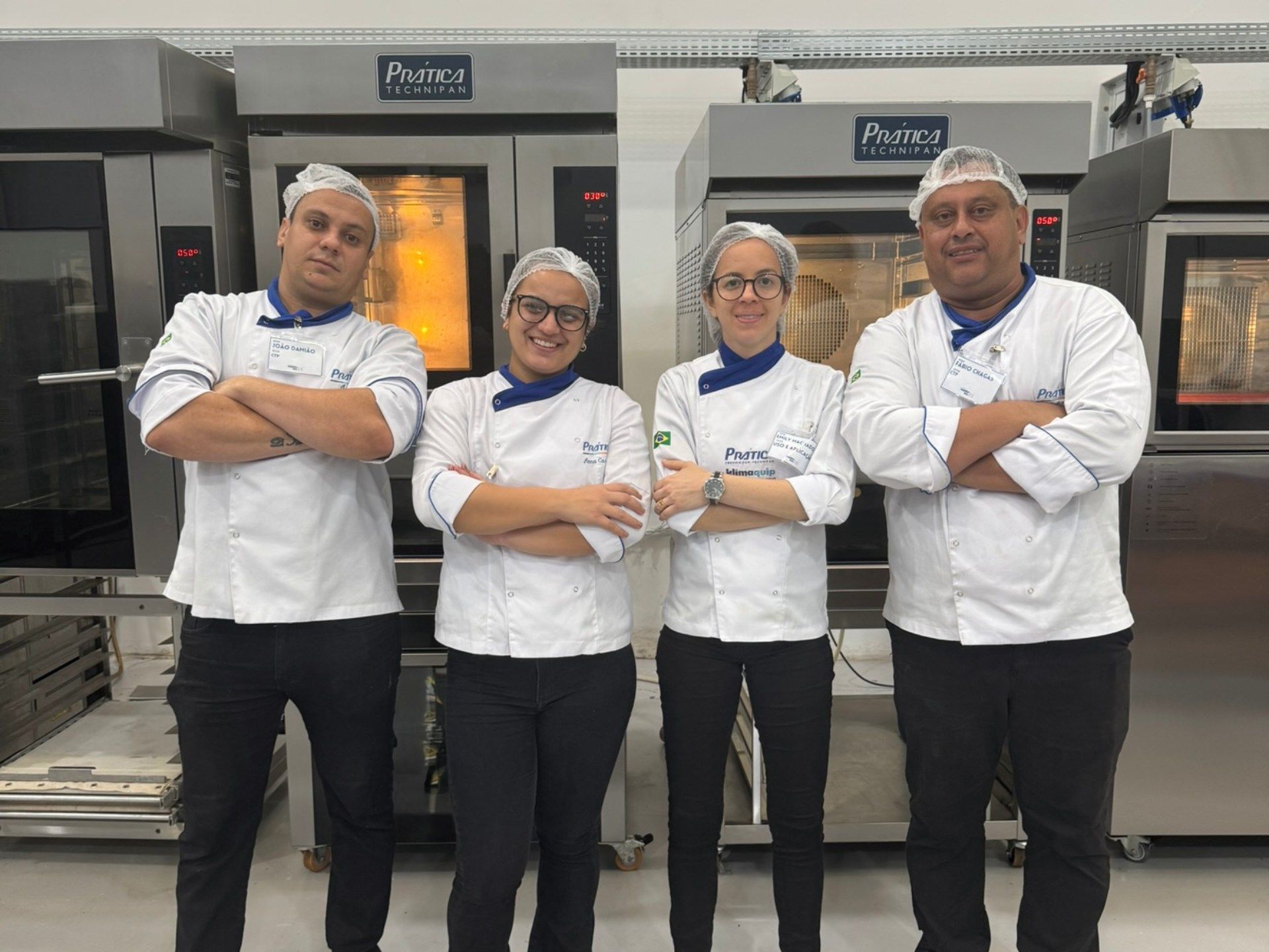 Um grupo de pessoas em pé, uma ao lado da outra, com os braços cruzados.