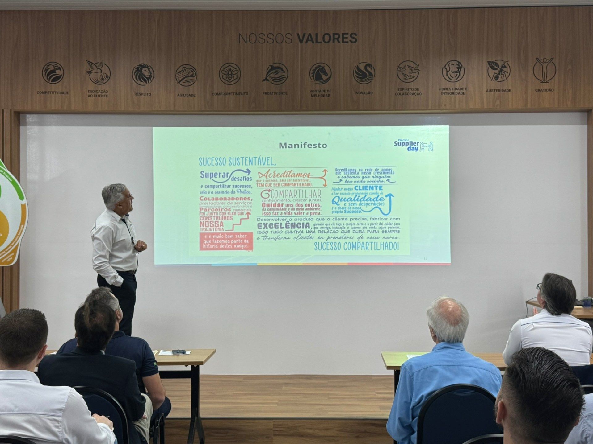 Um homem está fazendo uma apresentação para um grupo de pessoas em uma sala de aula.