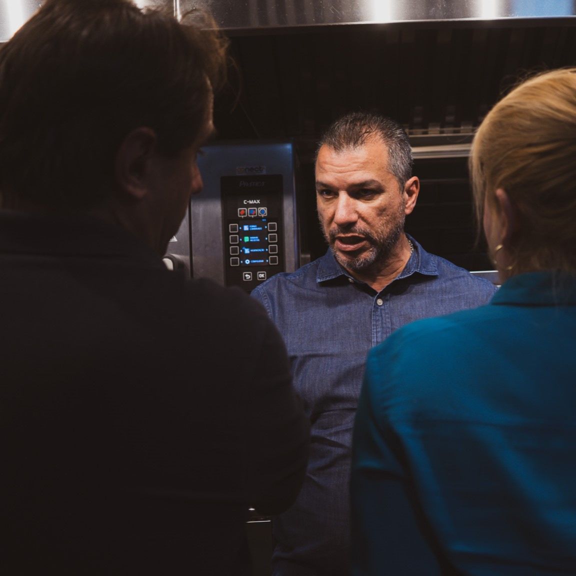 Um homem de camisa azul está conversando com uma mulher na cozinha