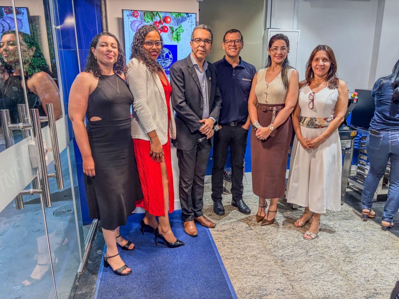 Grupo de seis pessoas posando para uma foto em um ambiente de escritório.