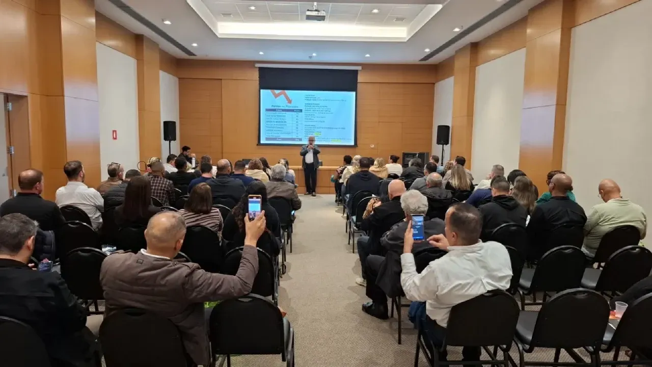 Um homem está fazendo uma apresentação para um grande grupo de pessoas em uma sala de conferências.