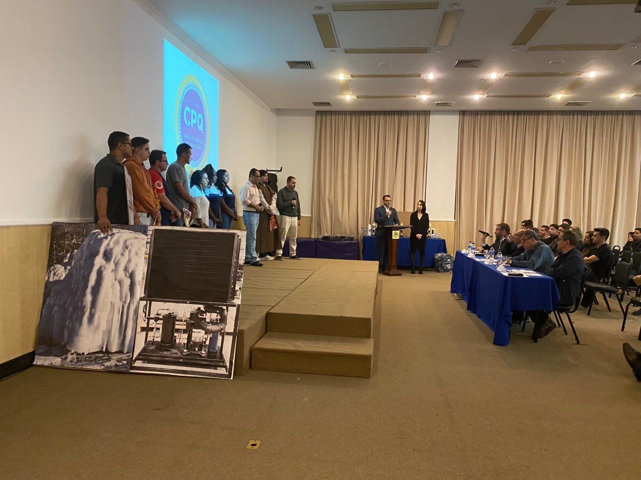 Um grupo de pessoas em pé em um palco em uma sala de conferências