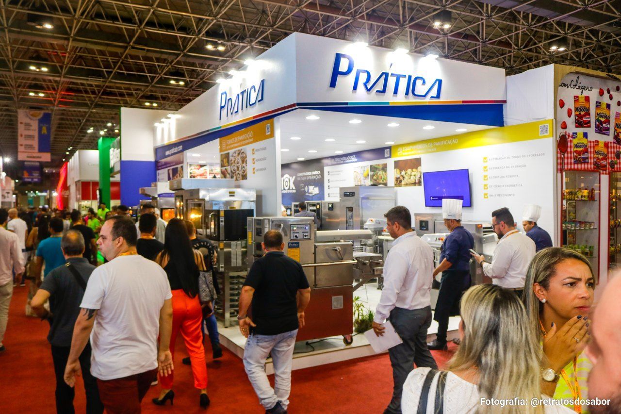 Um grupo de pessoas está andando em volta de um estande em uma convenção.