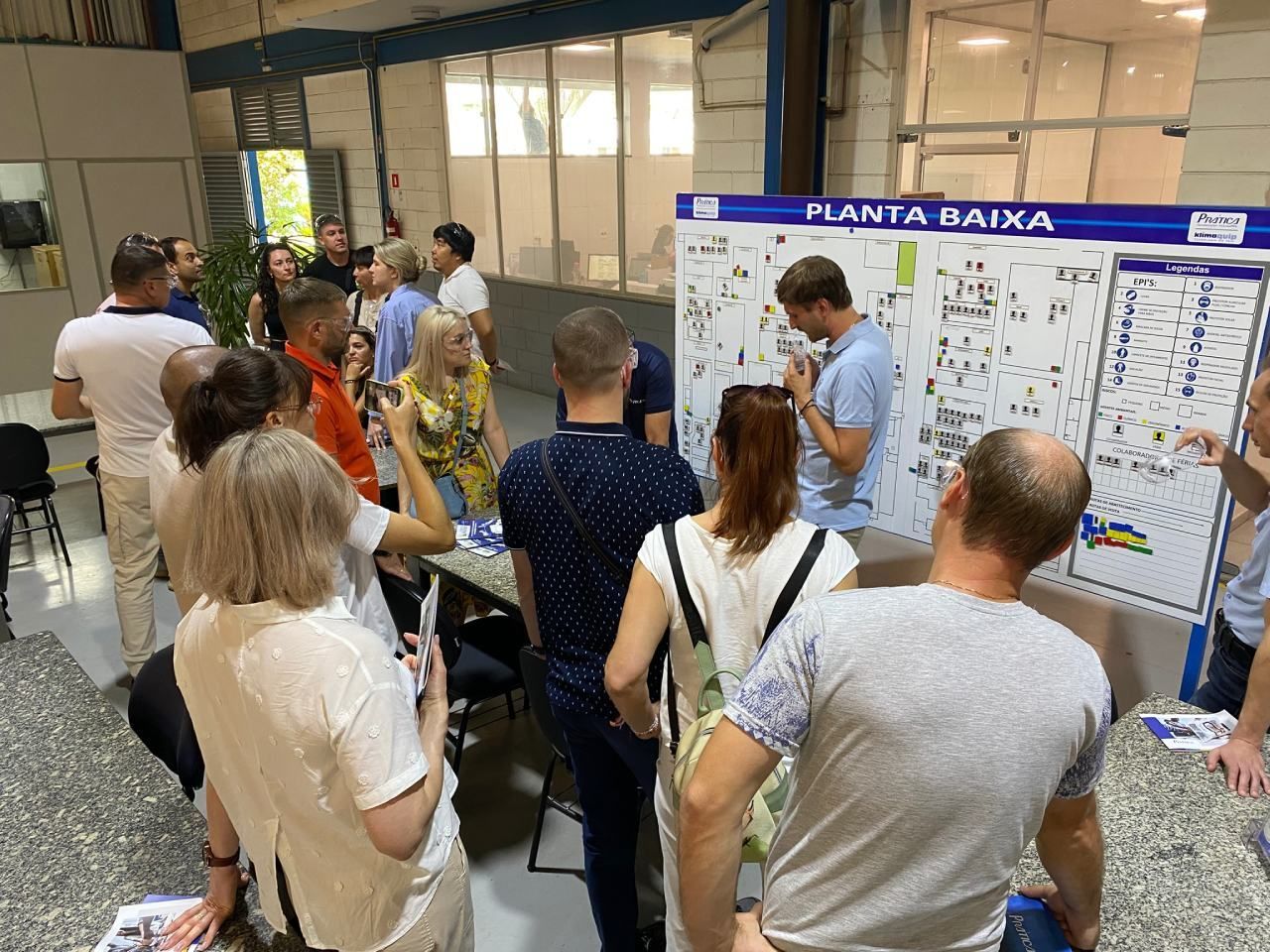 Um grupo de pessoas está em pé ao redor de um quadro branco em uma sala.