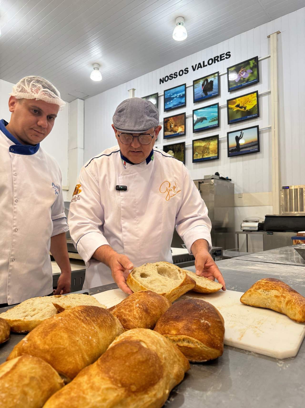 Dois homens estão de pé ao lado de uma mesa com pão sobre ela.