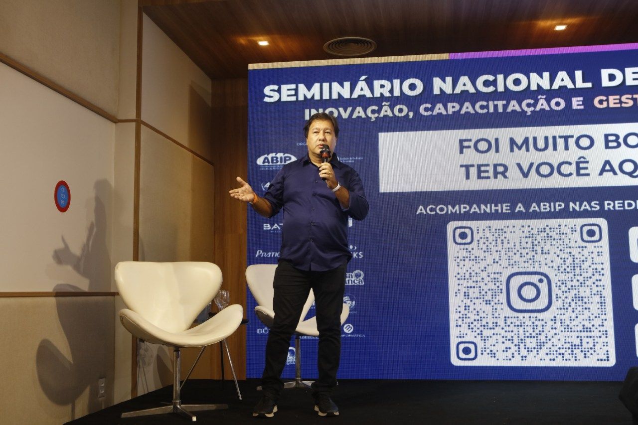 Um homem está parado em frente a uma placa que diz seminário nacional
