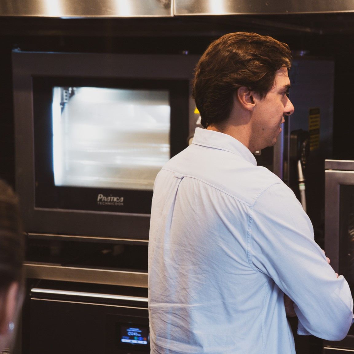 Um homem de camisa branca está parado em frente a um forno Panera