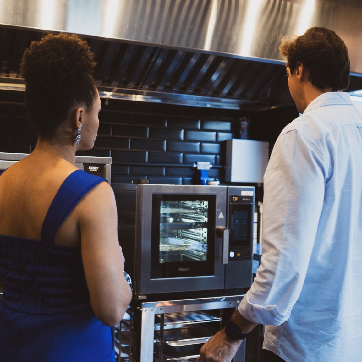 Um homem e uma mulher estão olhando para um micro-ondas em uma cozinha