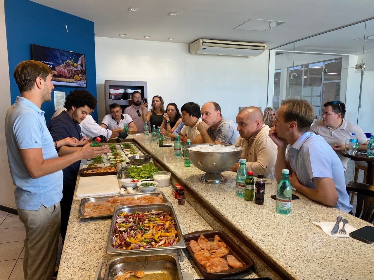 Um grupo de pessoas está sentado em uma mesa longa comendo.