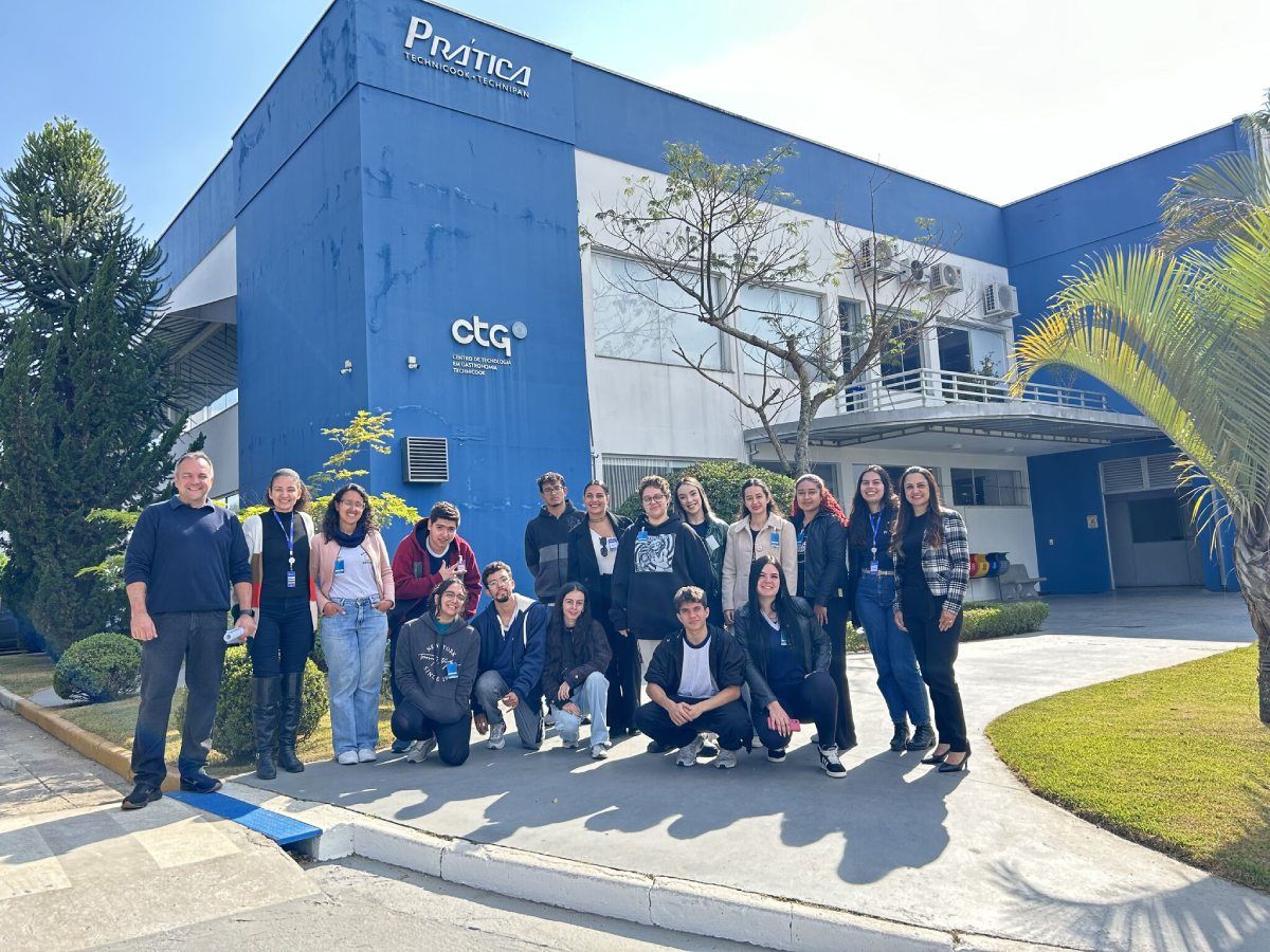 Um grupo de pessoas está posando para uma foto em frente a um prédio azul.