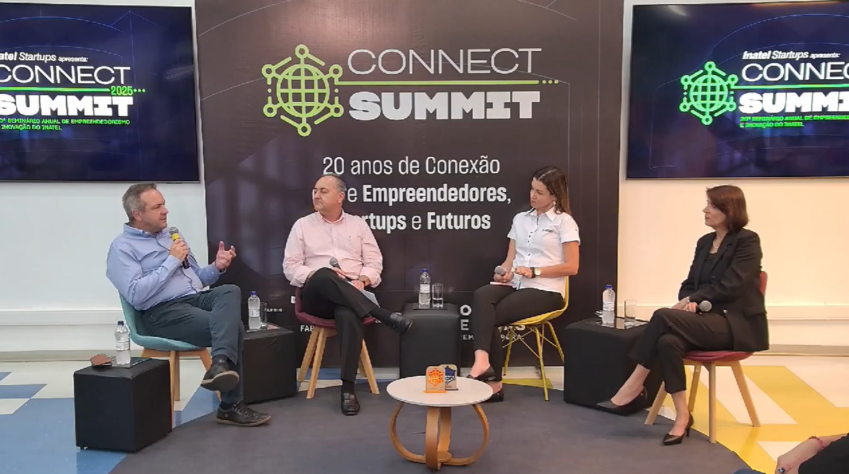 Painel no Connect Summit, com quatro pessoas sentadas, discutindo. Fundo preto, logotipo visível.