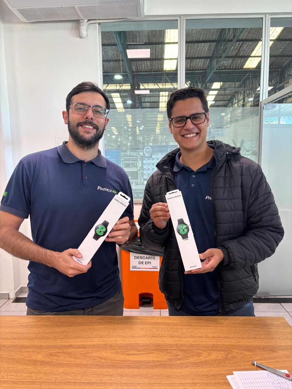 Dois homens estão parados um ao lado do outro segurando relógios nas mãos.