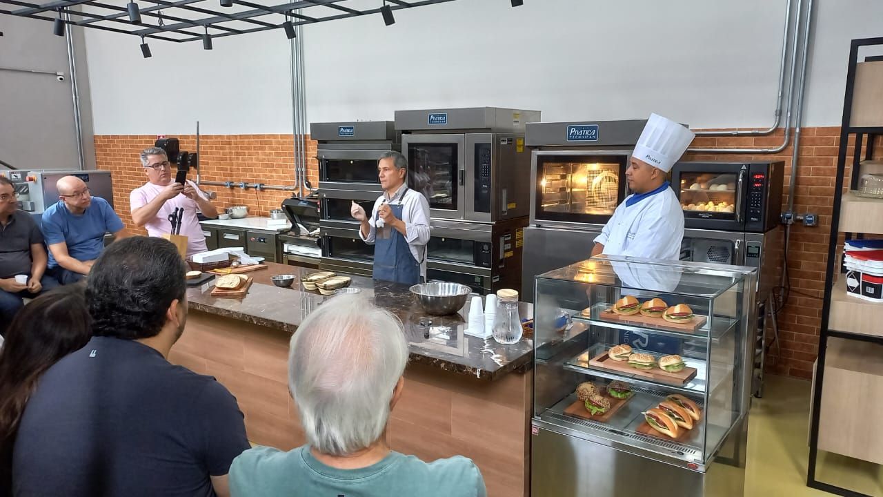 Um grupo de pessoas está sentado em frente a um chef em uma cozinha.